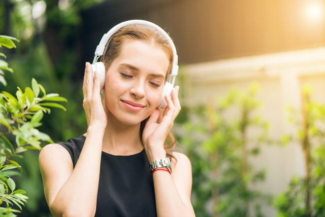 woman-wearing-black-sleeveless-dress-holding-white-headphone-1001850